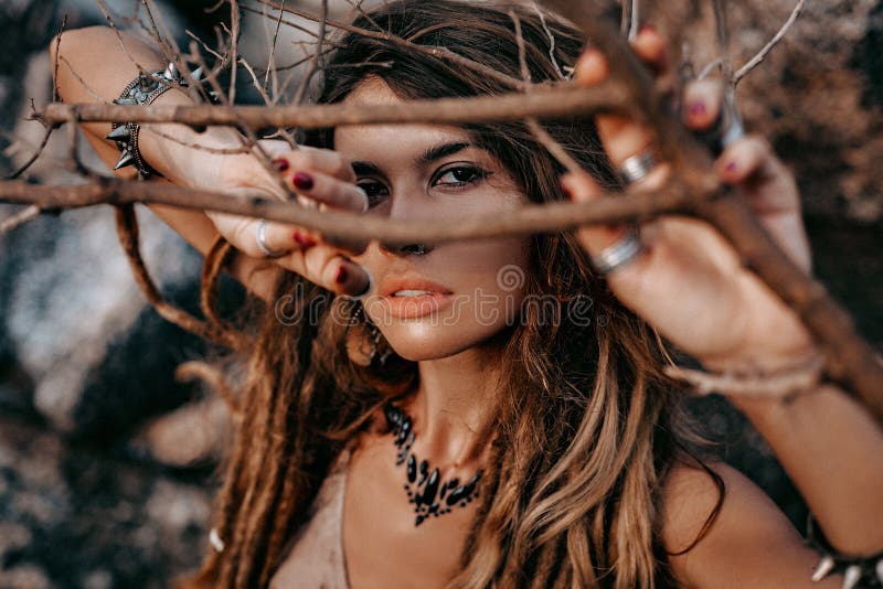 Retrato ascendente cercano de la mujer joven hermosa que mira in camera a través de ramas secas