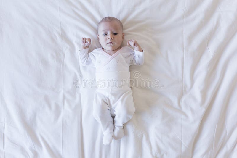 Retrato ascendente cercano de un bebé hermoso en el fondo blanco en casa que mira la cámara foto de archivo libre de regalías