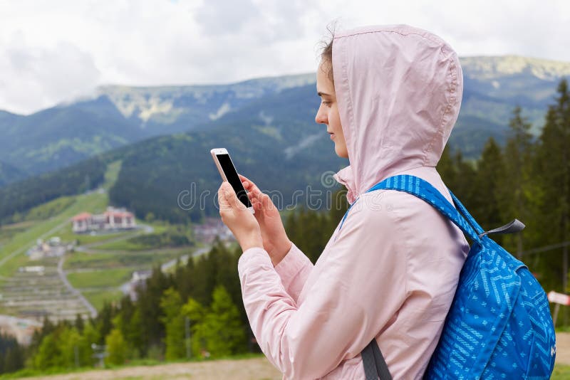 Retrato ascendente cercano del perfil de la mujer joven del caminante con la mochila azul que toma las fotografías del paisaje he foto de archivo libre de regalías Retrato ascendente cercano del perfil de la mujer joven del caminante con la mochila azul que toma las fotografías del paisaje he foto de archivo libre de regalías