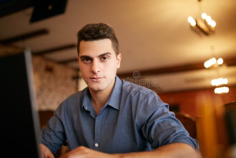 Retrato auténtico del hombre de negocios confiado joven que mira la cámara con el ordenador portátil en oficina Hombre del inconf fotos de archivo Retrato auténtico del hombre de negocios confiado joven que mira la cámara con el ordenador portátil en oficina Hombre del inconf fotos de archivo