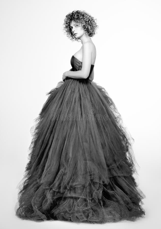 Retrato blanco y negro de la moda de la mujer joven hermosa en un vestido gris largo foto de archivo Retrato blanco y negro de la moda de la mujer joven hermosa en un vestido gris largo foto de archivo
