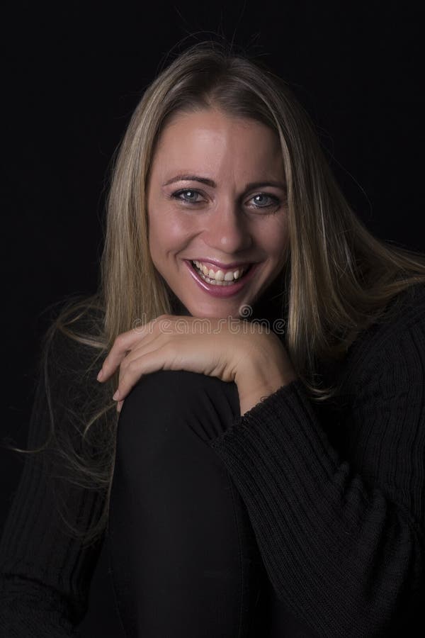 Retrato bonito da mulher na luminosidade reduzida que senta-se no sofá de couro marrom imagem de stock Retrato bonito da mulher na luminosidade reduzida que senta-se no sofá de couro marrom imagem de stock
