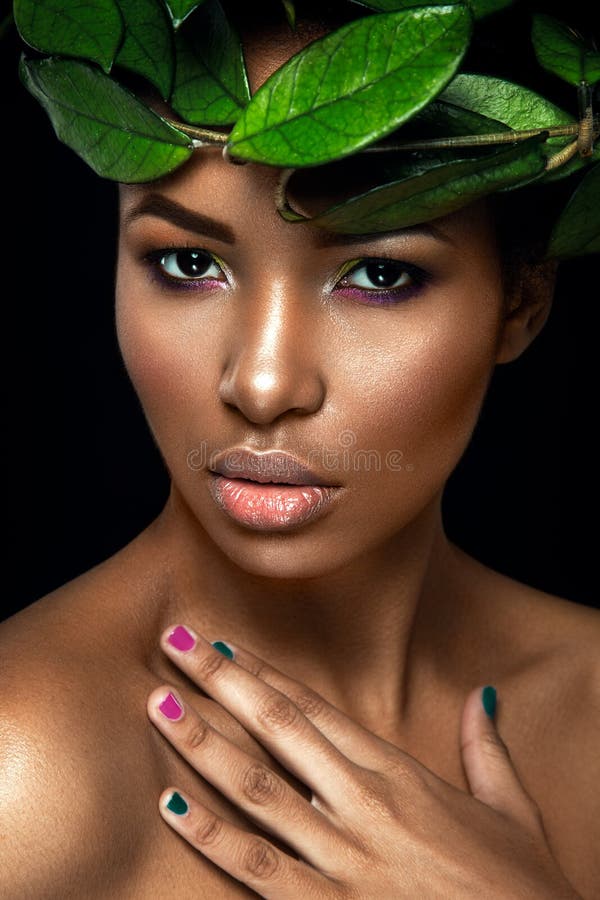 Retrato bonito da mulher no fundo preto Menina afro nova que levanta com folhas verdes Lindo compõe imagens de stock