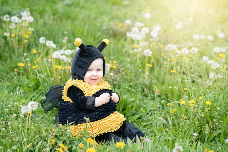 retrato bonito e alegre de uma criança sentada em flores florescentes de dandelion em fantasia de abelha amarela fotografia de stock retrato bonito e alegre de uma criança sentada em flores florescentes de dandelion em fantasia de abelha amarela fotografia de stock