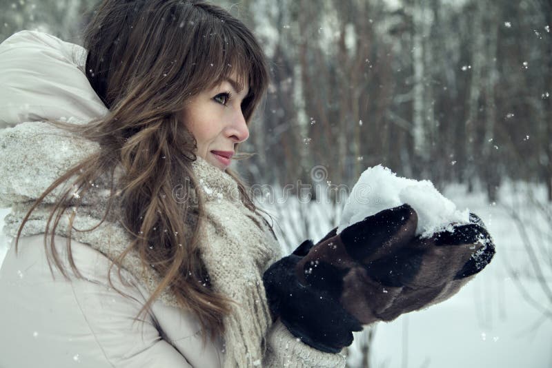 Retrato bonito novo da mulher na floresta do inverno com neve nas mãos imagem de stock Retrato bonito novo da mulher na floresta do inverno com neve nas mãos imagem de stock