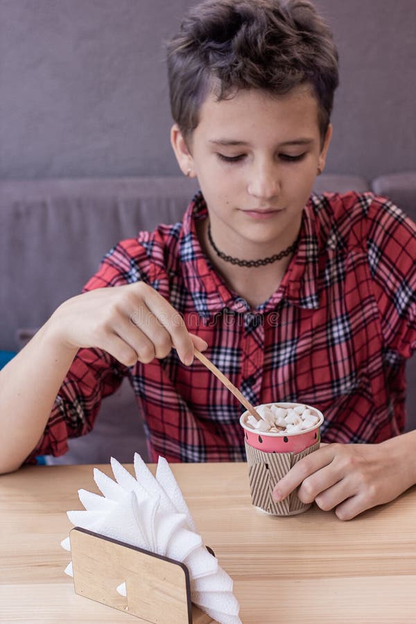 Casual portrait of half-length teenage girl with trendy short hairdo in hipster style clothes drinking cocoa with marshmallows. Soft focus, blurred background. Casual portrait of half-length teenage girl with trendy short hairdo in hipster style clothes drinking cocoa with marshmallows. Soft focus, blurred background