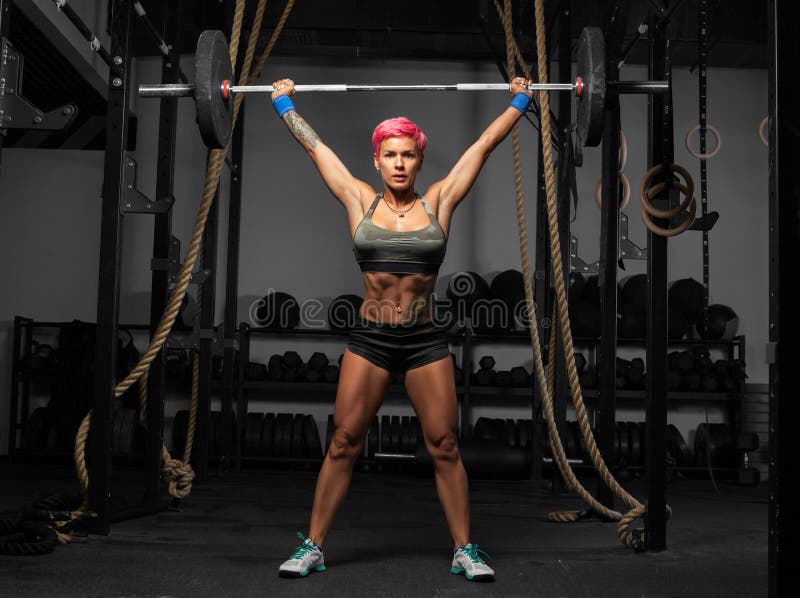 Retrato completo do comprimento da mulher muscular em um gym que faz exercícios pesados fotografia de stock Retrato completo do comprimento da mulher muscular em um gym que faz exercícios pesados fotografia de stock