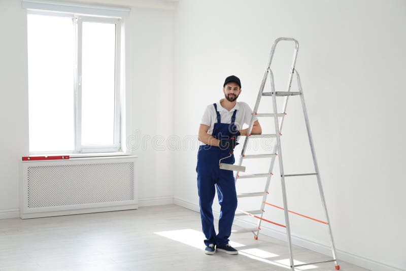 Retrato completo do comprimento do trabalhador manual com a escova do rolo perto da escada dentro Ferramentas profissionais da co fotos de stock royalty free Retrato completo do comprimento do trabalhador manual com a escova do rolo perto da escada dentro Ferramentas profissionais da co fotos de stock royalty free