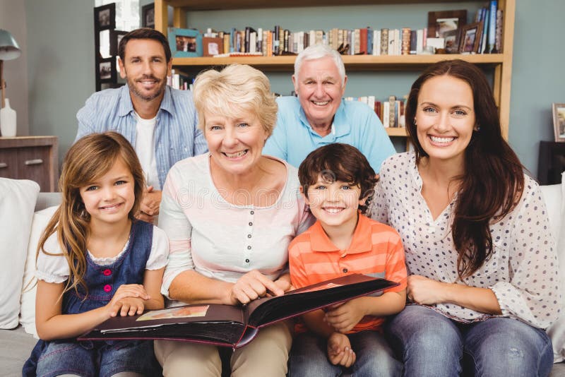 Retrato da família de sorriso com as avós que guardam o álbum de fotografias foto de stock Retrato da família de sorriso com as avós que guardam o álbum de fotografias foto de stock