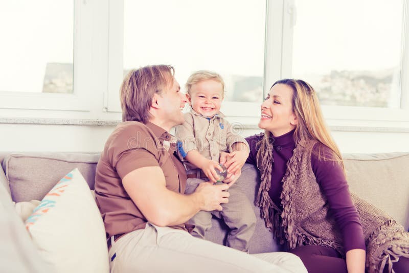 Retrato da família feliz que senta-se no sofá e no jogo fotos de stock Retrato da família feliz que senta-se no sofá e no jogo fotos de stock