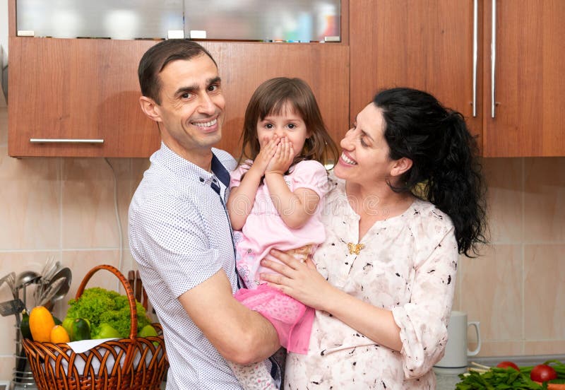 Retrato da família no interior da cozinha com frutas e legumes frescas, a menina saudável do conceito do alimento, da mulher grav imagens de stock royalty free Retrato da família no interior da cozinha com frutas e legumes frescas, a menina saudável do conceito do alimento, da mulher grav imagens de stock royalty free