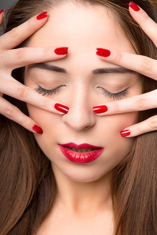 Retrato da fêmea nova atrativa, olhos fechados, com verniz para as unhas vermelho, em dar fotografia de stock