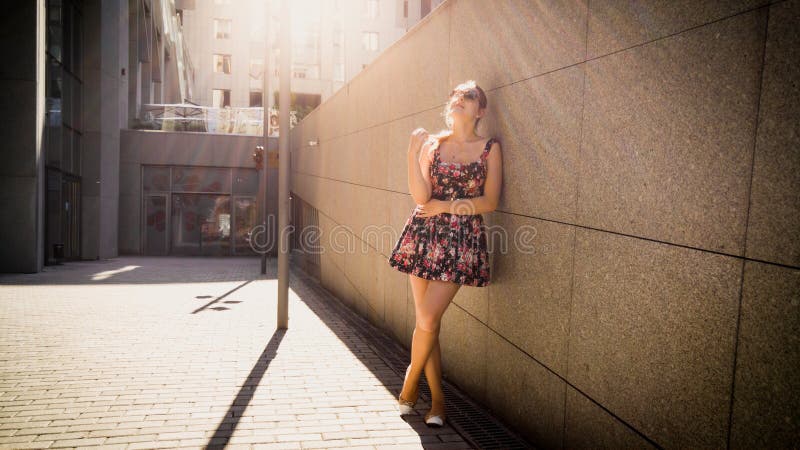 Retrato da jovem mulher bonita no vestido curto que inclina-se contra a parede de pedra na rua da cidade e que olha in camera imagem de stock royalty free Retrato da jovem mulher bonita no vestido curto que inclina-se contra a parede de pedra na rua da cidade e que olha in camera imagem de stock royalty free