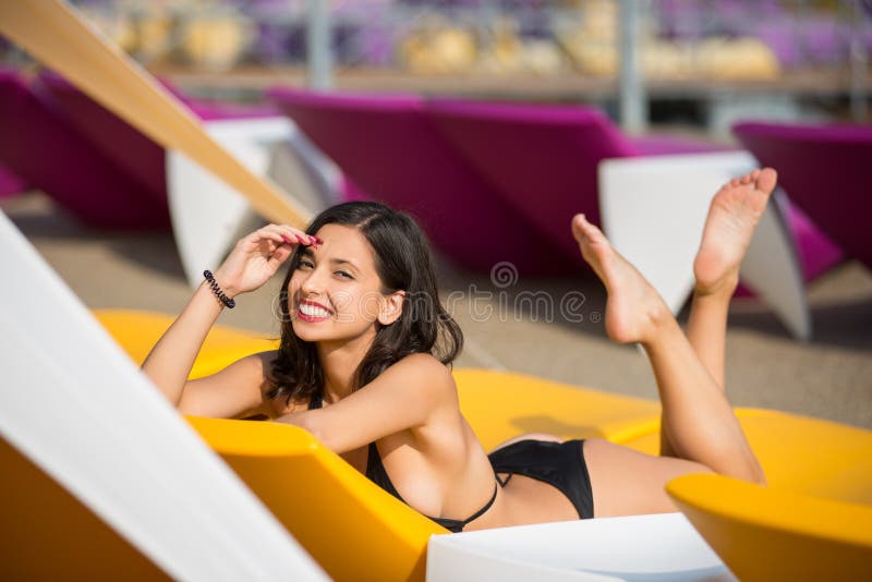 Retrato da jovem mulher com um corpo perfeito em um biquini preto que encontra-se em um vadio amarelo no recurso luxuoso fotos de stock Retrato da jovem mulher com um corpo perfeito em um biquini preto que encontra-se em um vadio amarelo no recurso luxuoso fotos de stock