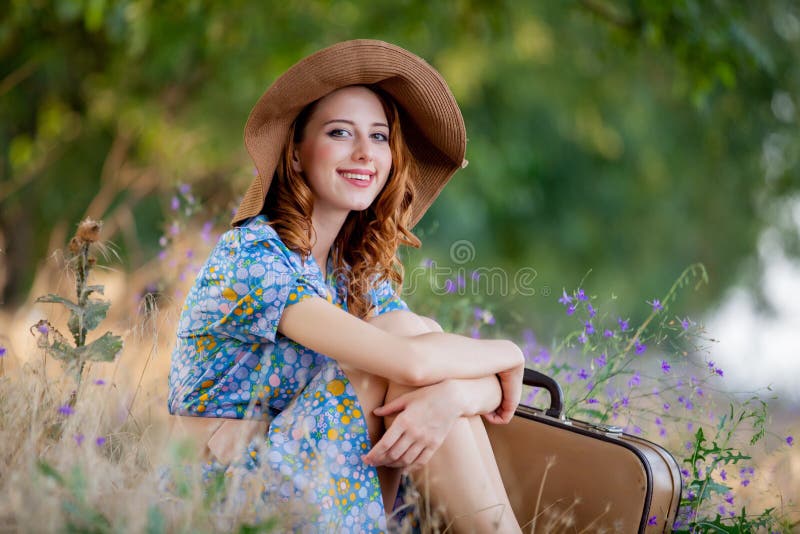Retrato da menina adulta no vestido azul no chapéu com mala de viagem foto de stock royalty free Retrato da menina adulta no vestido azul no chapéu com mala de viagem foto de stock royalty free
