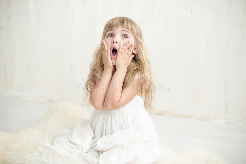 Retrato da menina bonita no vestido branco, é surpreendida e posta suas mãos sobre mordentes fotos de stock Retrato da menina bonita no vestido branco, é surpreendida e posta suas mãos sobre mordentes fotos de stock