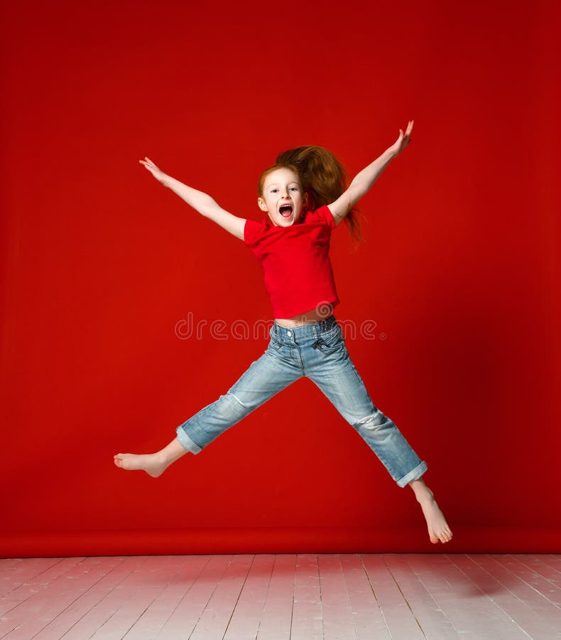 Retrato da menina feliz que salta acima das m?os de levantamento altas isoladas no fundo vermelho foto de stock royalty free Retrato da menina feliz que salta acima das m?os de levantamento altas isoladas no fundo vermelho foto de stock royalty free