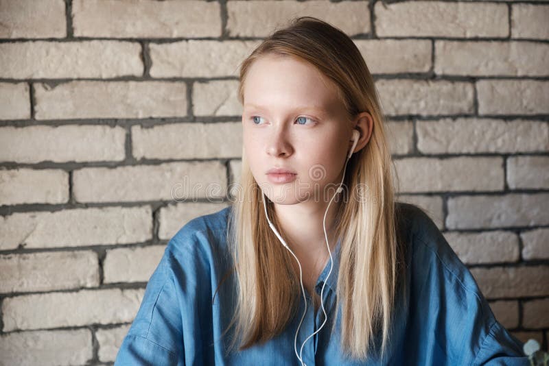 Retrato da menina loura nova com fones de ouvido imagem de stock royalty free Retrato da menina loura nova com fones de ouvido imagem de stock royalty free