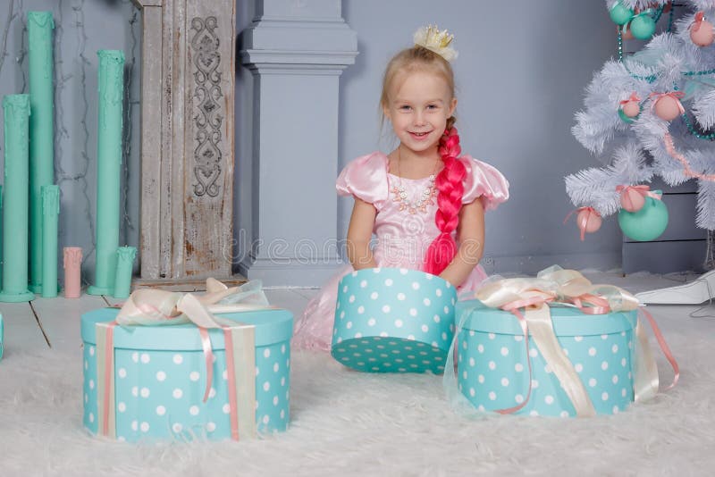 Retrato da menina loura pequena europeia bonito da princesa com a coroa no vestido bonito que senta-se no assoalho e nos presente imagens de stock Retrato da menina loura pequena europeia bonito da princesa com a coroa no vestido bonito que senta-se no assoalho e nos presente imagens de stock