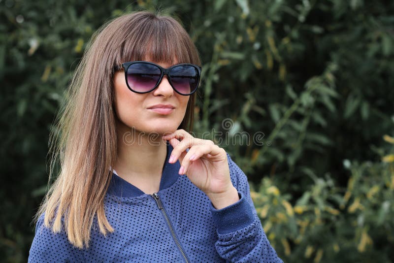 Retrato da moça atrativa no parque contra plantas verdes Menina bonita nos óculos de sol Adolescente elegante imagem de stock Retrato da moça atrativa no parque contra plantas verdes Menina bonita nos óculos de sol Adolescente elegante imagem de stock