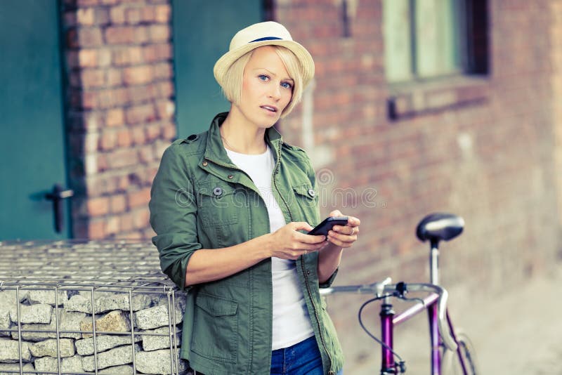 Retrato da mulher do moderno com telefone e bicicleta fotografia de stock royalty free Retrato da mulher do moderno com telefone e bicicleta fotografia de stock royalty free