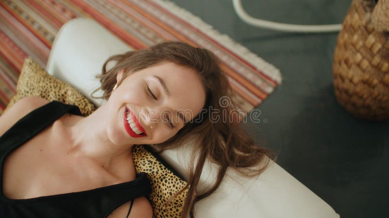 Retrato da mulher moreno bonita nova que encontra-se no sofá e que sorri a uma câmera imagens de stock royalty free Retrato da mulher moreno bonita nova que encontra-se no sofá e que sorri a uma câmera imagens de stock royalty free
