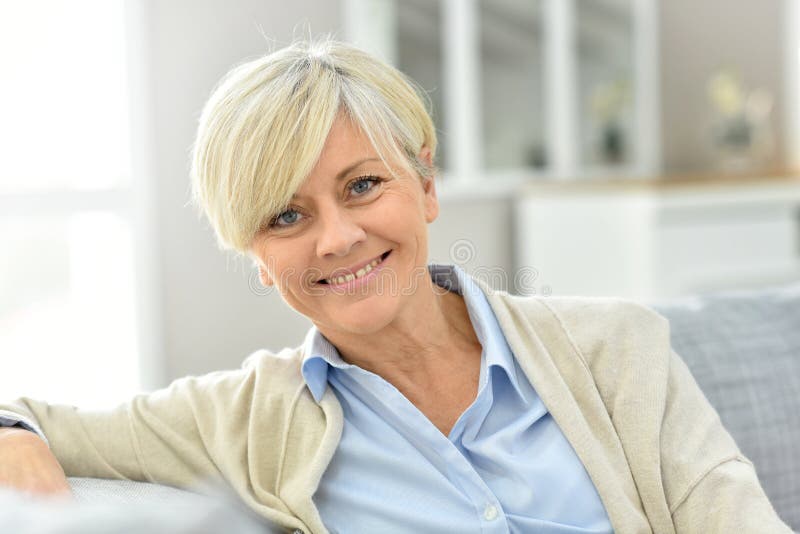 Retrato da mulher superior que sorri e que relaxa no sofá imagem de stock Retrato da mulher superior que sorri e que relaxa no sofá imagem de stock