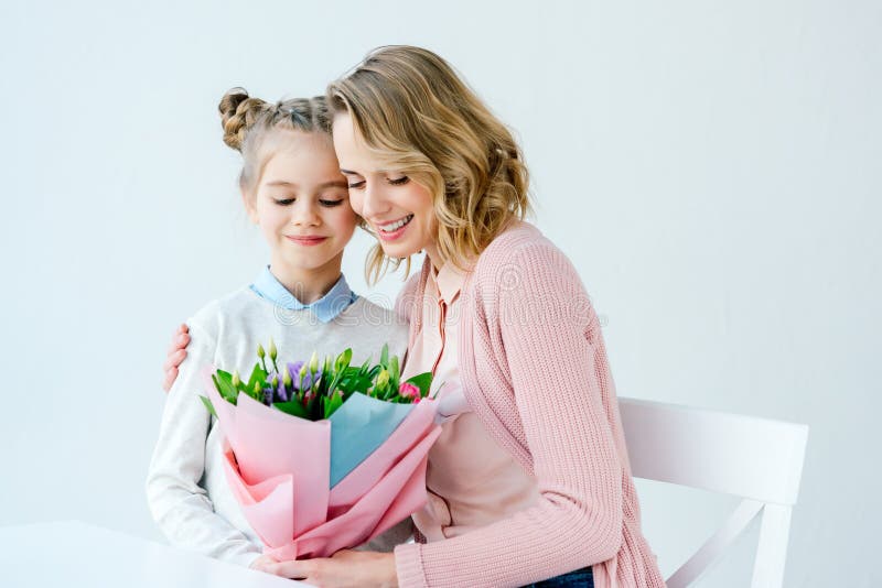 retrato da mãe de sorriso que abraça a filha pequena com o ramalhete bonito das flores, mães felizes foto de stock retrato da mãe de sorriso que abraça a filha pequena com o ramalhete bonito das flores, mães felizes foto de stock