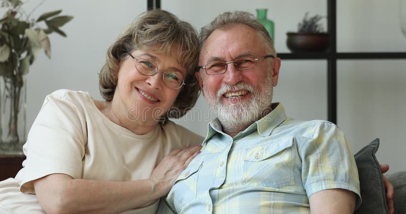 Retrato de cabeza feliz pareja mayor casada abrazándose en el sofá riendo metrajes