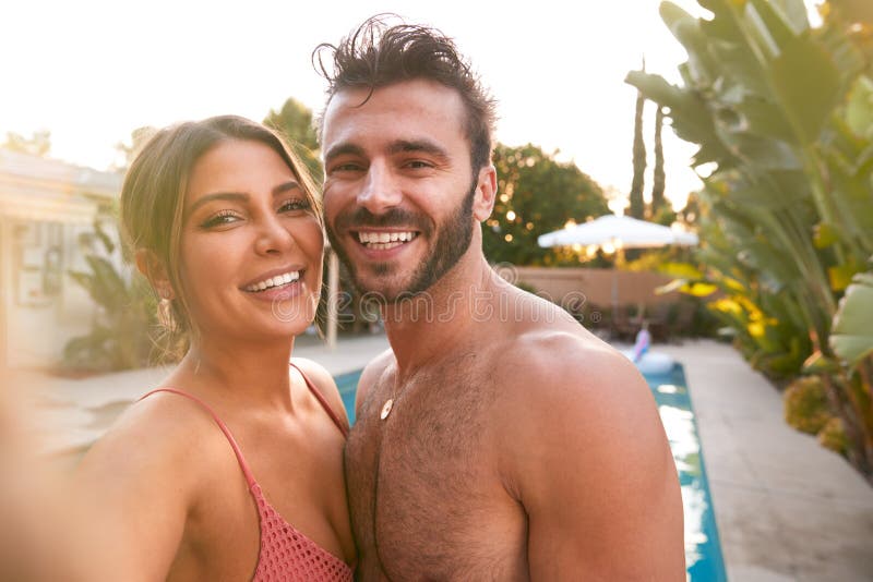 Retrato de casal romântico na festa da piscina de verão tomando selfie no celular