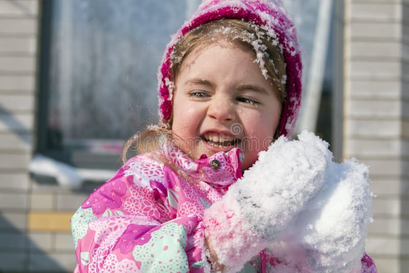 Retrato de cerca de una linda niñita divirtiéndose en la nieve fotos de archivo