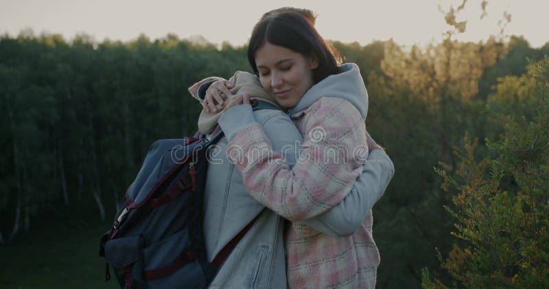 Retrato de chicas y chicos besando y abrazando expresando amor parado en un hermoso bosque montañoso en un día soleado