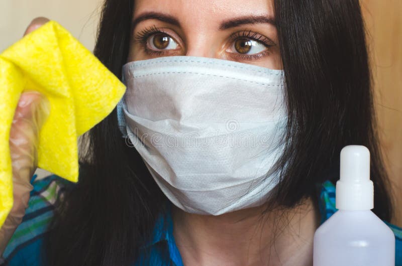 Retrato de cierre de una mujer con una máscara de protección contra el virus médico con un trapo y un agente antibacteriano fotografía de archivo libre de regalías