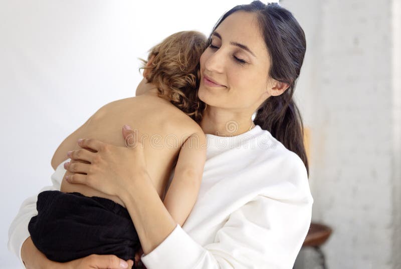 Retrato de clausura de un lindo bebé con una encantadora madre con ropa blanca casual imagen de archivo libre de regalías