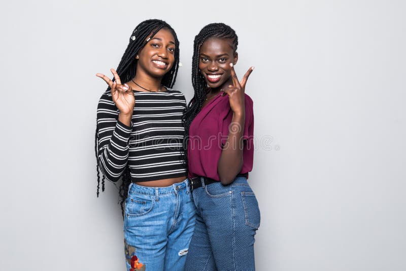 Retrato de dos novias africanas que muestran la muestra de dos fingeres aislada en fondo gris imagen de archivo Retrato de dos novias africanas que muestran la muestra de dos fingeres aislada en fondo gris imagen de archivo