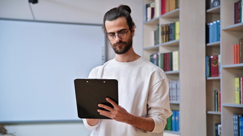Retrato de escritura masculina en el portapapeles en la biblioteca almacen de video