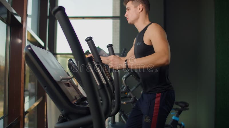 Retrato de fitness hombre calentarse antes de entrenarse en entrenador elíptico en el gimnasio club Cardio de formación masculina metrajes