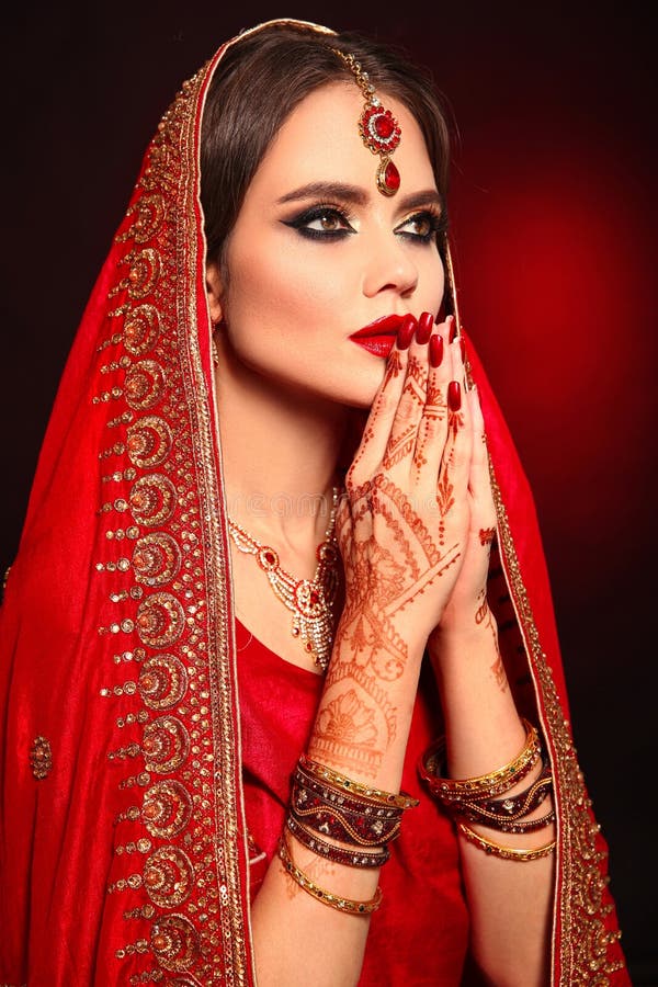 Portrait of beautiful indian girl in red bridal sari. Young hindu woman model with kundan jewelry set. Traditional Indian costume lehenga choli. Henna painting, mehendi on bride`s hands. Portrait of beautiful indian girl in red bridal sari. Young hindu woman model with kundan jewelry set. Traditional Indian costume lehenga choli. Henna painting, mehendi on bride`s hands