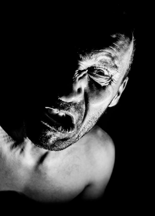 Retrato de hombre caucásico adulto con cara muy enojada y que parece maniático o diabólico. grita a alguien. blanco y negro fotos de archivo libres de regalías