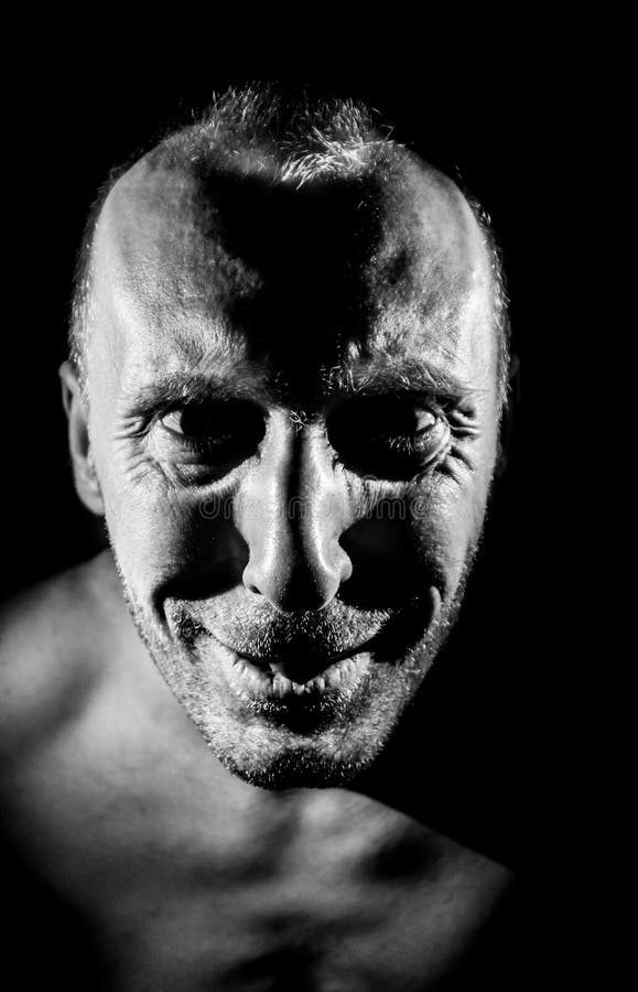 Retrato de hombre caucásico adulto. sonríe como maniático y parece locura. iluminación en blanco y negro de disparo. aislado fotos de archivo