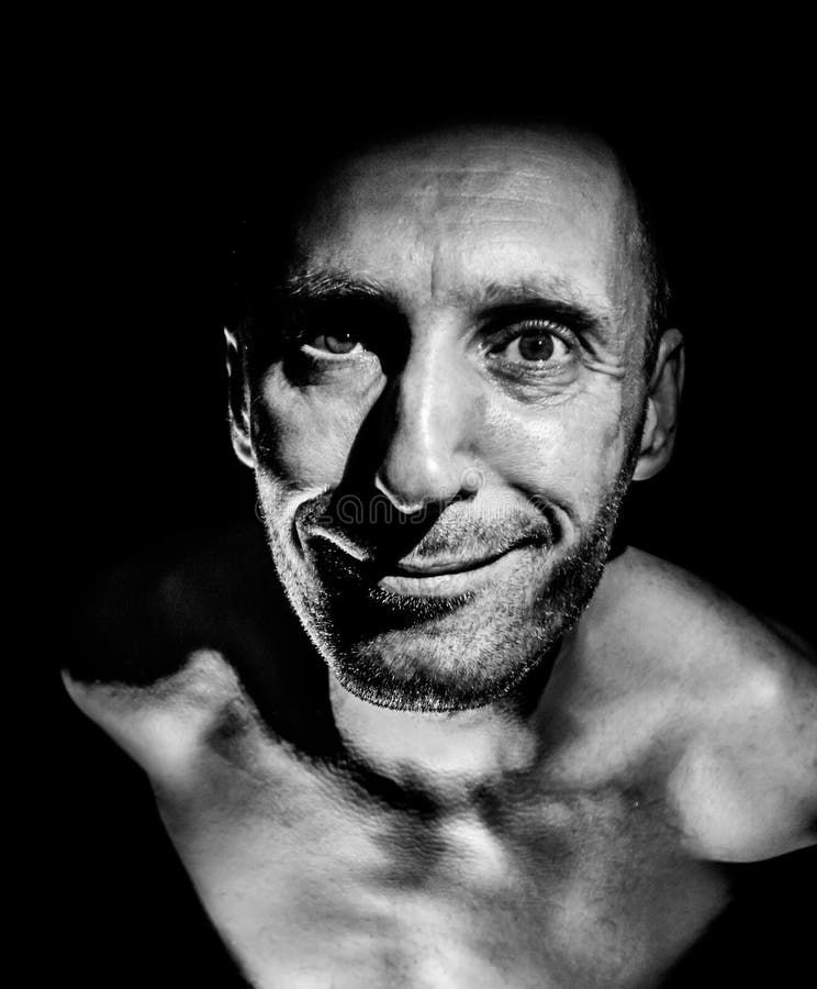 Retrato de hombre caucásico adulto. sonríe como maniático y parece locura. iluminación en blanco y negro de disparo. aislado foto de archivo