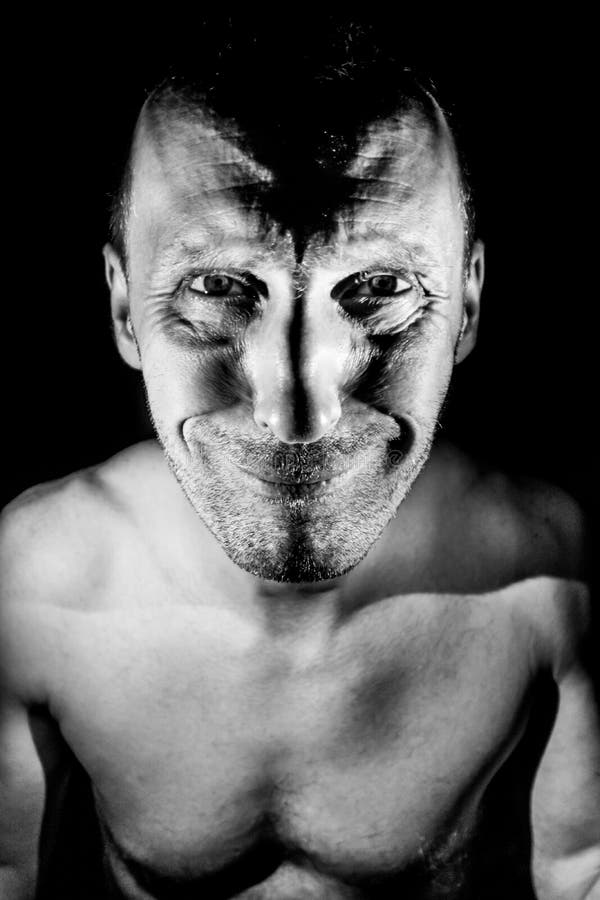 Retrato de hombre caucásico adulto. sonríe como maniático y parece locura. iluminación en blanco y negro de disparo fotos de archivo