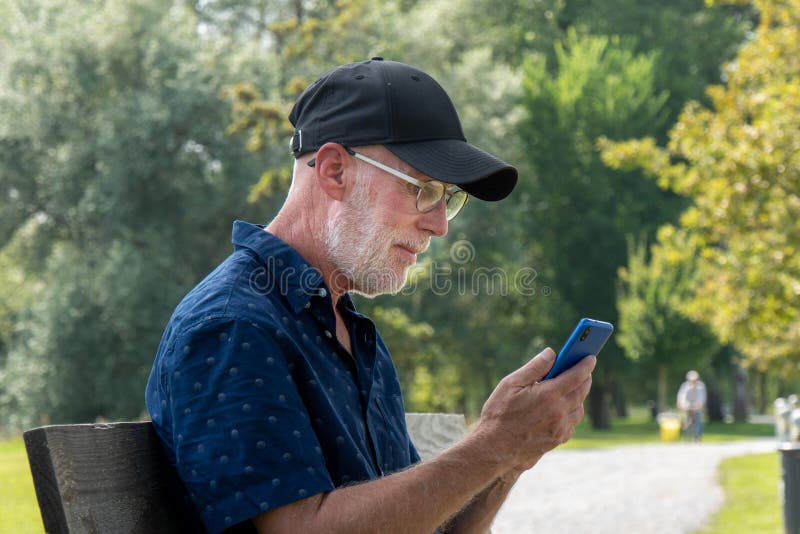 Retrato de hombre mayor con barba y gafas usando smartphone fotos de archivo libres de regalías Retrato de hombre mayor con barba y gafas usando smartphone fotos de archivo libres de regalías