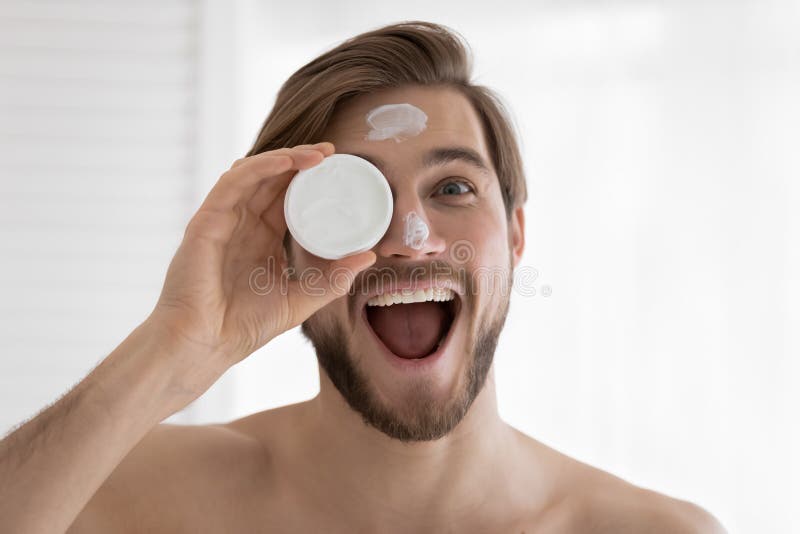 Retrato de imagen de cabeza joven gracioso sosteniendo un frasco de crema imagen de archivo