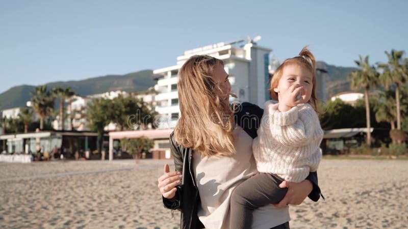 Retrato de joven madre con pequeña hija divirtiéndose en la playa almacen de metraje de vídeo