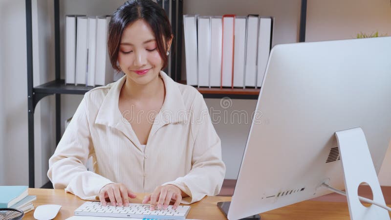 Retrato de joven mujer de negocios asiática trabajando con computadora de escritorio mientras se considera la planificación financ almacen de metraje de vídeo