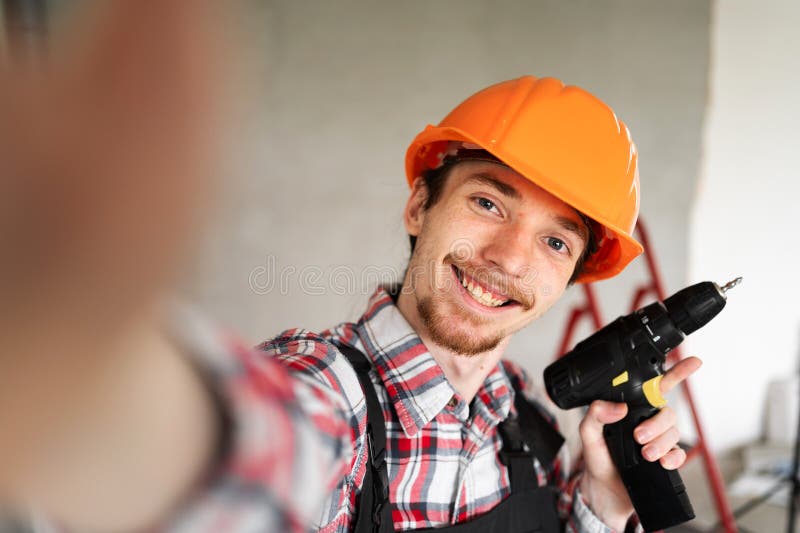Retrato de joven y feliz constructor con la toma de ejercicios de selfie sonriendo a la cámara imagen de archivo