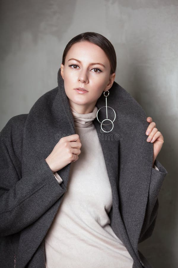 Retrato de la alta moda de la mujer elegante joven en estudio en la pared del vintage del greyconcrete Capa gris imagenes de archivo Retrato de la alta moda de la mujer elegante joven en estudio en la pared del vintage del greyconcrete Capa gris imagenes de archivo