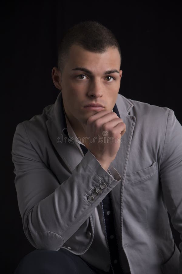 Retrato de la barbilla de reclinación hermosa del hombre joven en su mano imagen de archivo libre de regalías Retrato de la barbilla de reclinación hermosa del hombre joven en su mano imagen de archivo libre de regalías