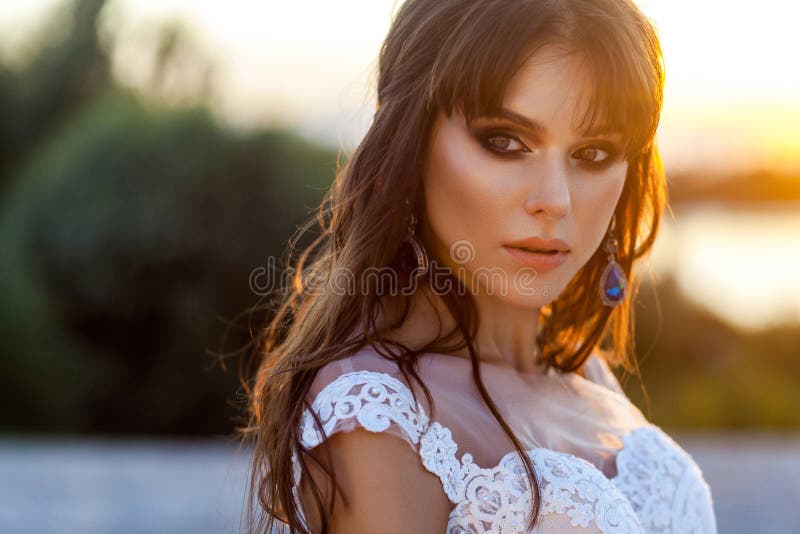 Retrato de la belleza del primer de la mujer morena tranquila linda con el vestido que se casa blanco que lleva del maquillaje y foto de archivo libre de regalías Retrato de la belleza del primer de la mujer morena tranquila linda con el vestido que se casa blanco que lleva del maquillaje y foto de archivo libre de regalías